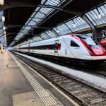 Czerwono– biały pociąg na zadaszonym dworcu.